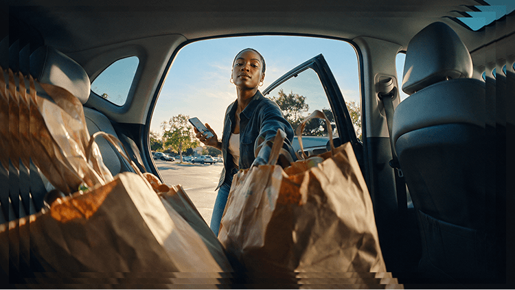Woman loading grocery bags into a car, with a Neo Advance balance of $74.38 overlaid on the image.