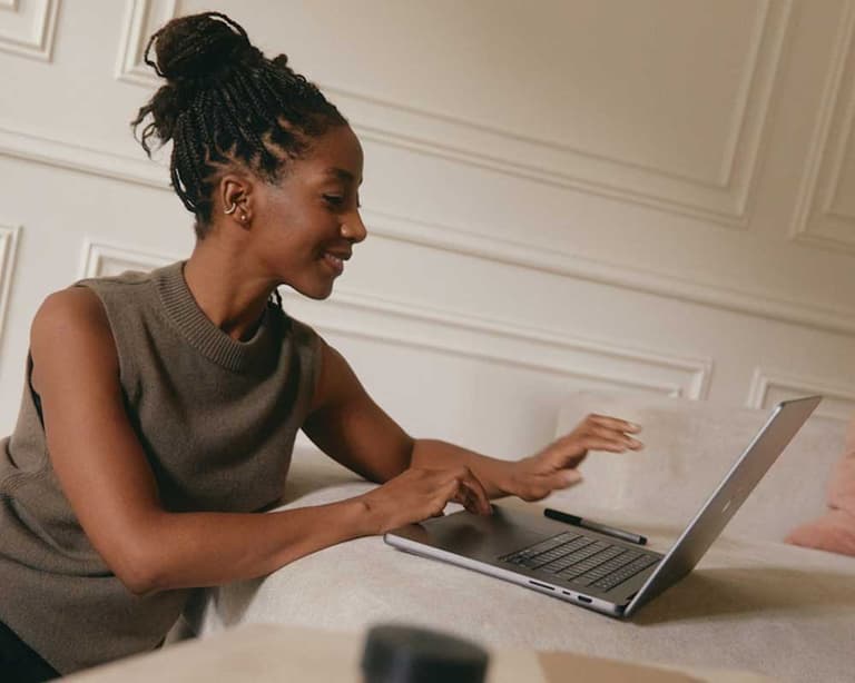 A young Canadian woman at home, applying for jobs on her desktop, as she reads headlines about the economy.