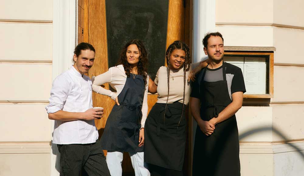 A group of servers outside a restaurant, smiling, as they know how much Canadians tip.