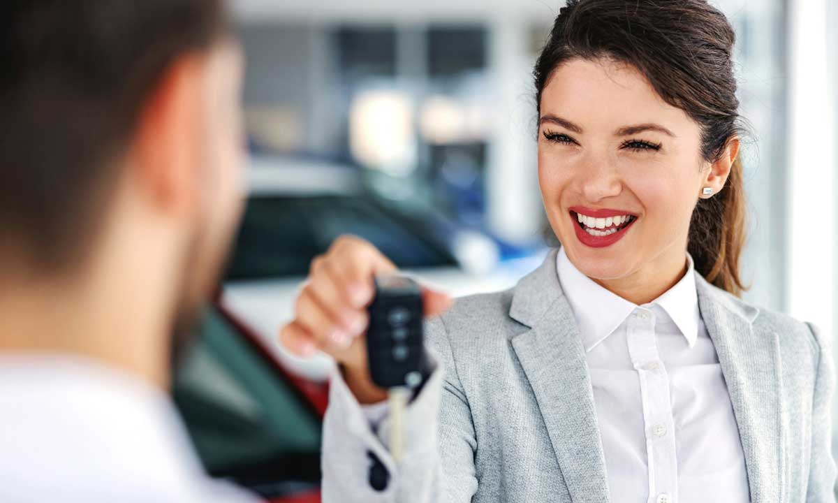 A car salesperson handing over keys for a vehicle to a new buyer. Car loans are one scam that is costing Canadians more.