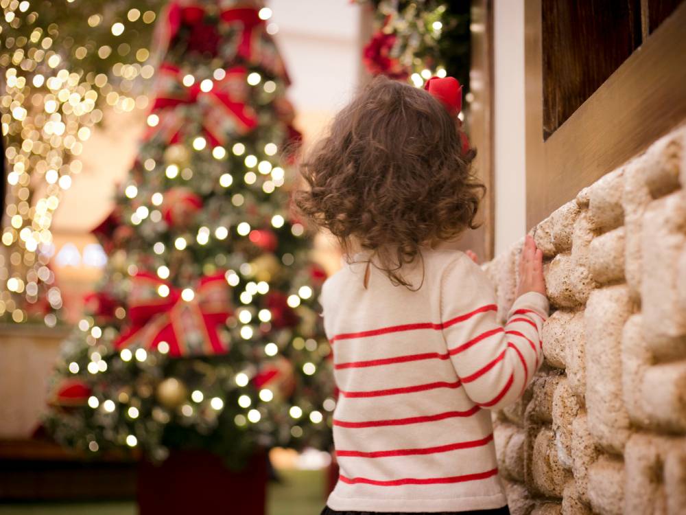 A little kid in from of a Christmas tree, hoping for one of the popular gifts for kids in Canada in 2025.