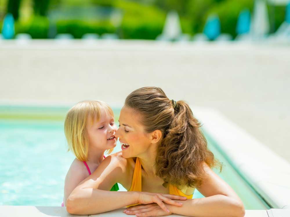 A Canadian family—mother and daughter—in the pool of an all-inclusive vacation resort. Find out if it's the cheapest way for Canadians to travel.