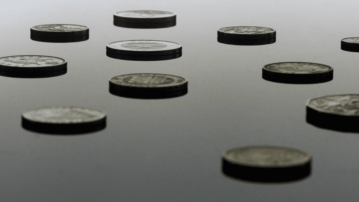 Coins of various currencies on a metal surface, representing cash advances as an alternative to Nyble's credit building loans
