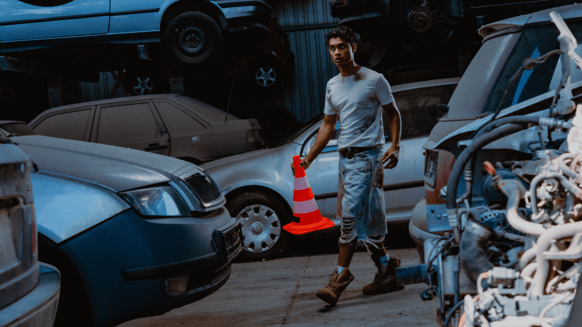 A man holding a traffic cone in a warehouse full of cars, representing how bad credit car loans in Canada can help people get cars with low credit scores