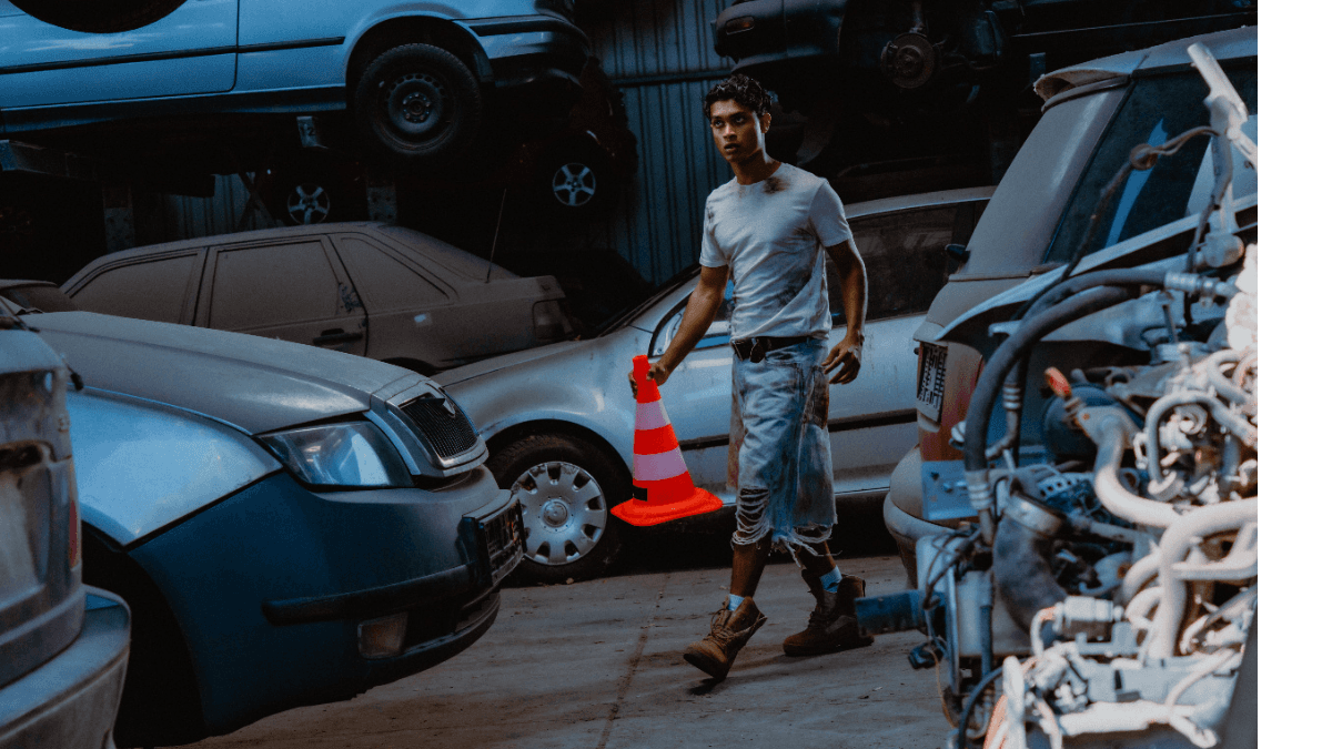 A man holding a traffic cone in a warehouse full of cars, representing how bad credit car loans in Canada can help people get cars with low credit scores