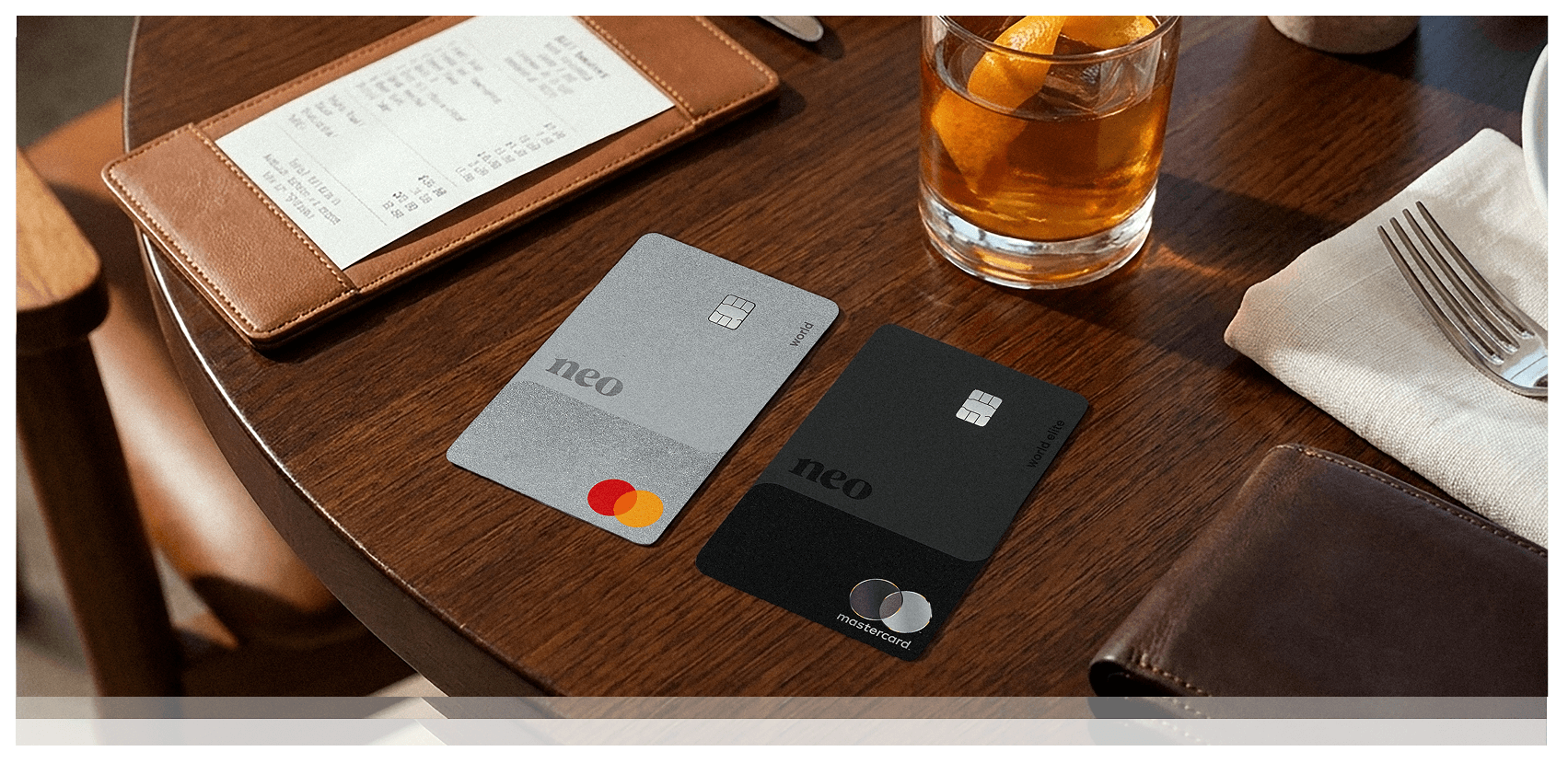 The Neo World Mastercard and Neo World Elite Mastercard - Shop & Dine, both optiosn for the best cash back credit cards in Canada, on a wooden table during a meal at a restaurant.