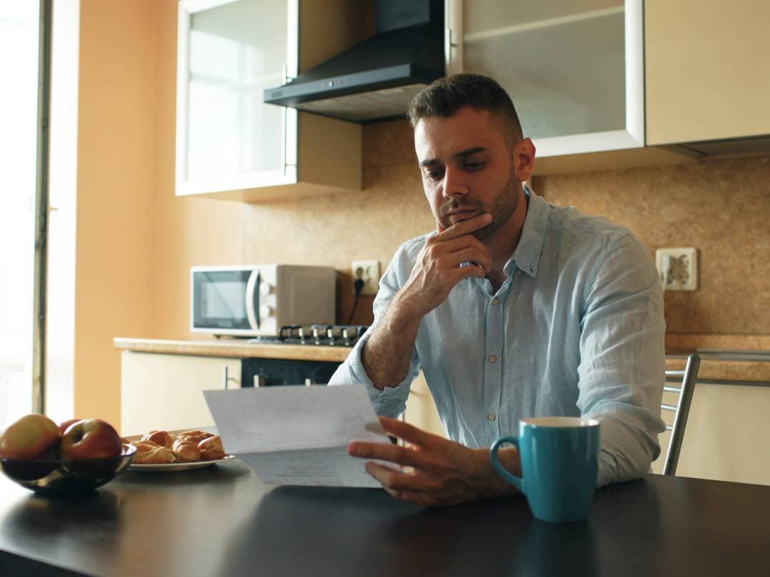 Canadian man looking at his credit card bill, wondering if the balance due is good for his credit score.
