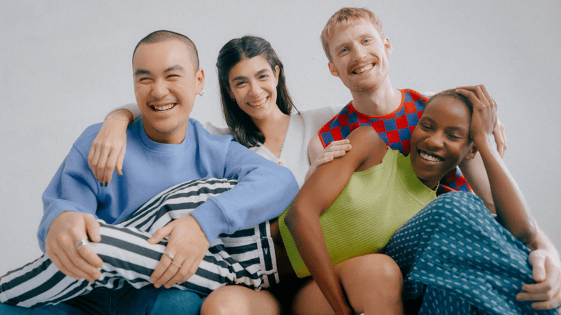 Four friends smiling as they hang out on a couch, talking about whether they can get credit cards as international students in Canada