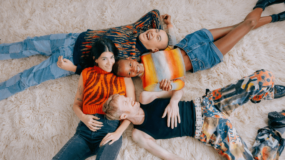 A group of four friends laying on a carpet, talking about how to build your credit from scratch as a Canadian immigrant