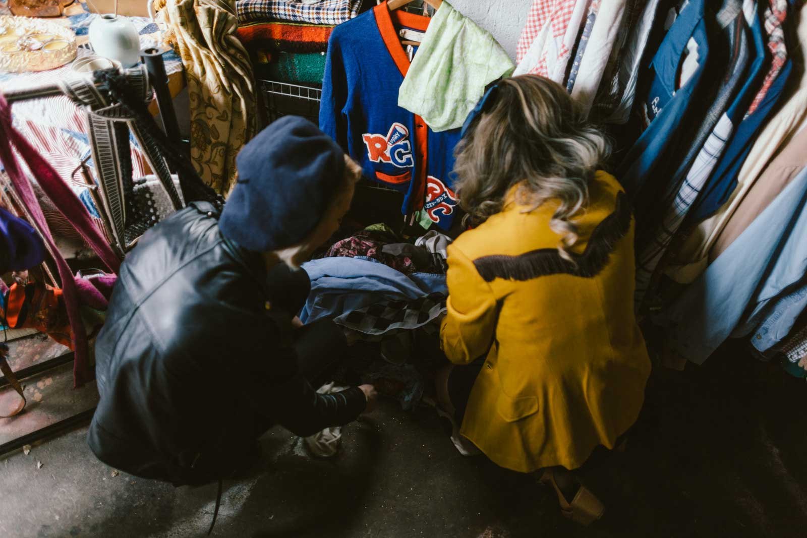 Two Canadians rummaging through boxes at a garage sale, trying to make a good deal.