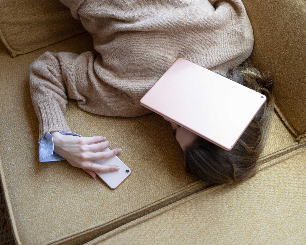 A Canadian woman, with her head under her iPad that won't work because of internet shortages, while also on the phone with the provider to negotiate a cheaper bill.
