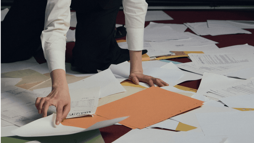 A person leaning over papers strewn on the floor, learning how to read a credit card statement