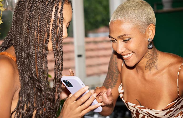 Two Canadian women, reading a phone message, trying to decide if a website is an AI scam.