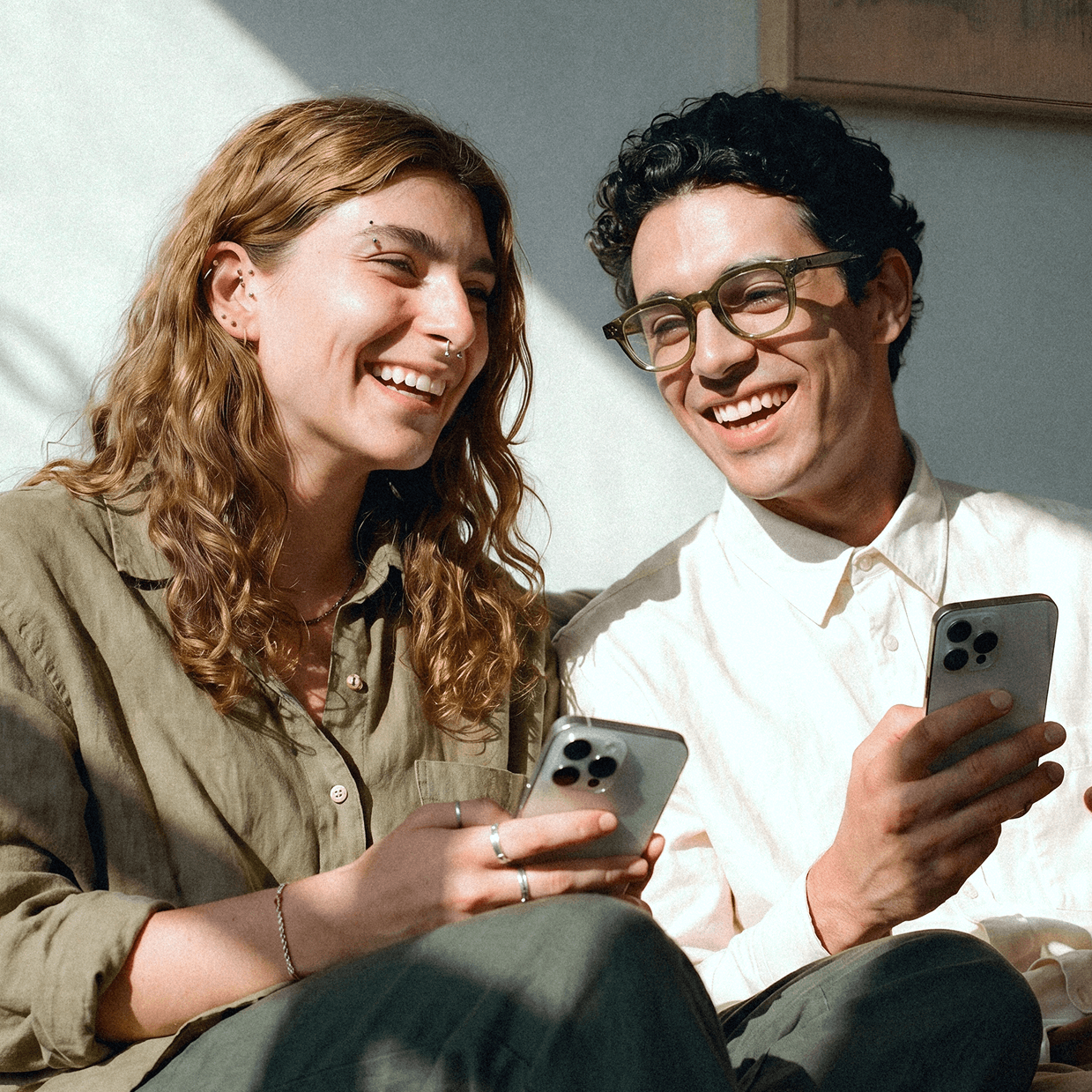 Two happy Canadians accessing their Joint Neo Chequing accounts on their mobile phones