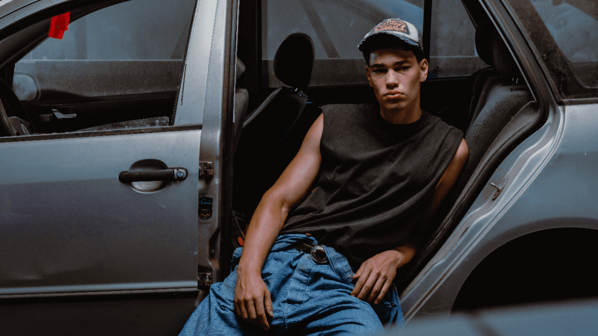 A persona leaning against the backseat of a car after securing a newcomer car loan in Canada