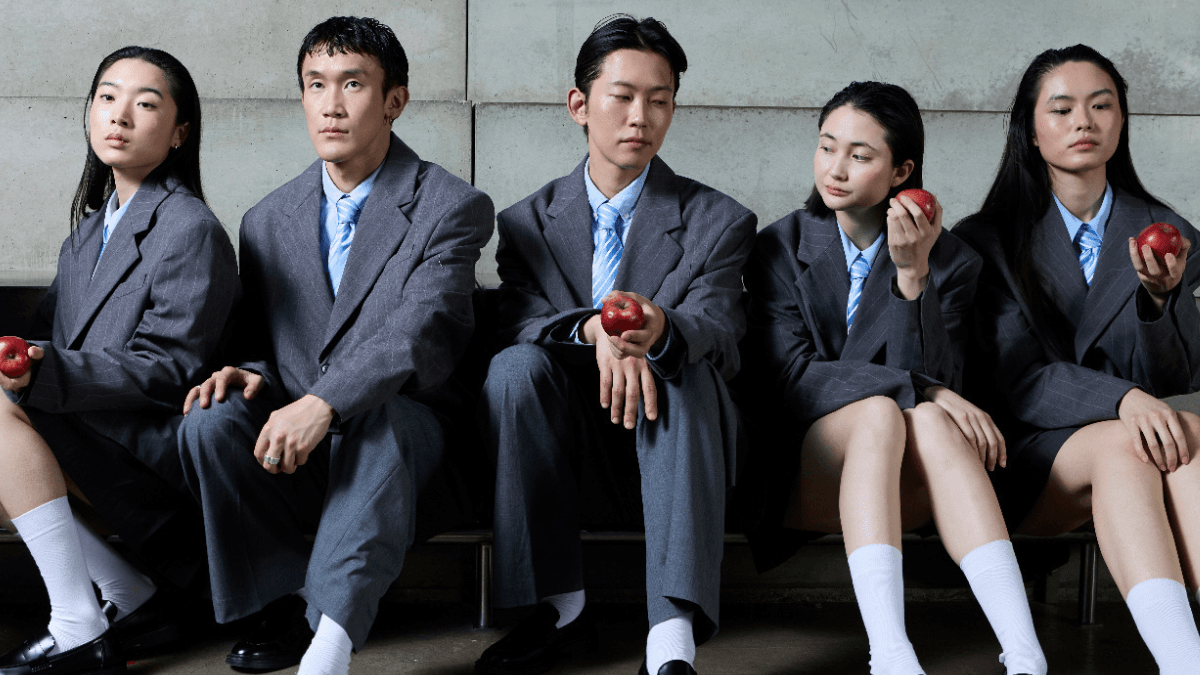 Five students in school uniforms, sitting side by side with apples in hand, wondering if they qualify for OSAP eligibility in Ontario