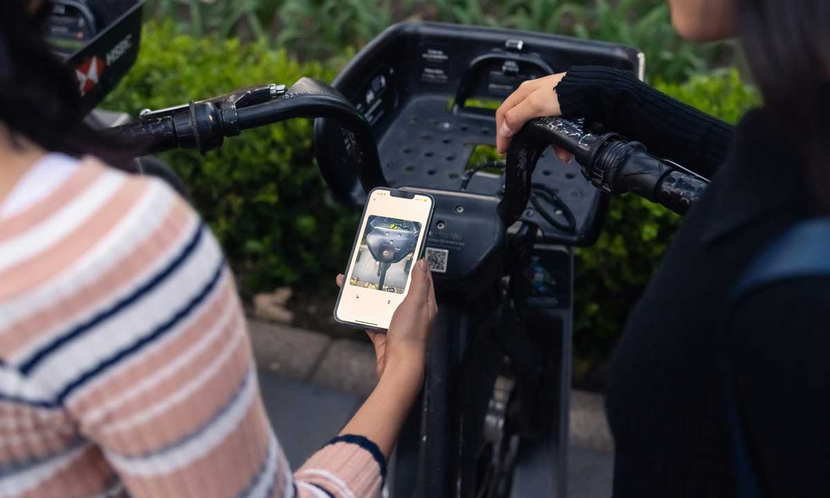 Two Canadian women taking a photo of a QR code to pay for a bike rental, but it could be a link to a phishing site for their credit card information.