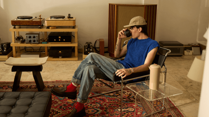 A person sits in a modern living room sipping coffee, wondering if they should open a high-interest savings account in Canada