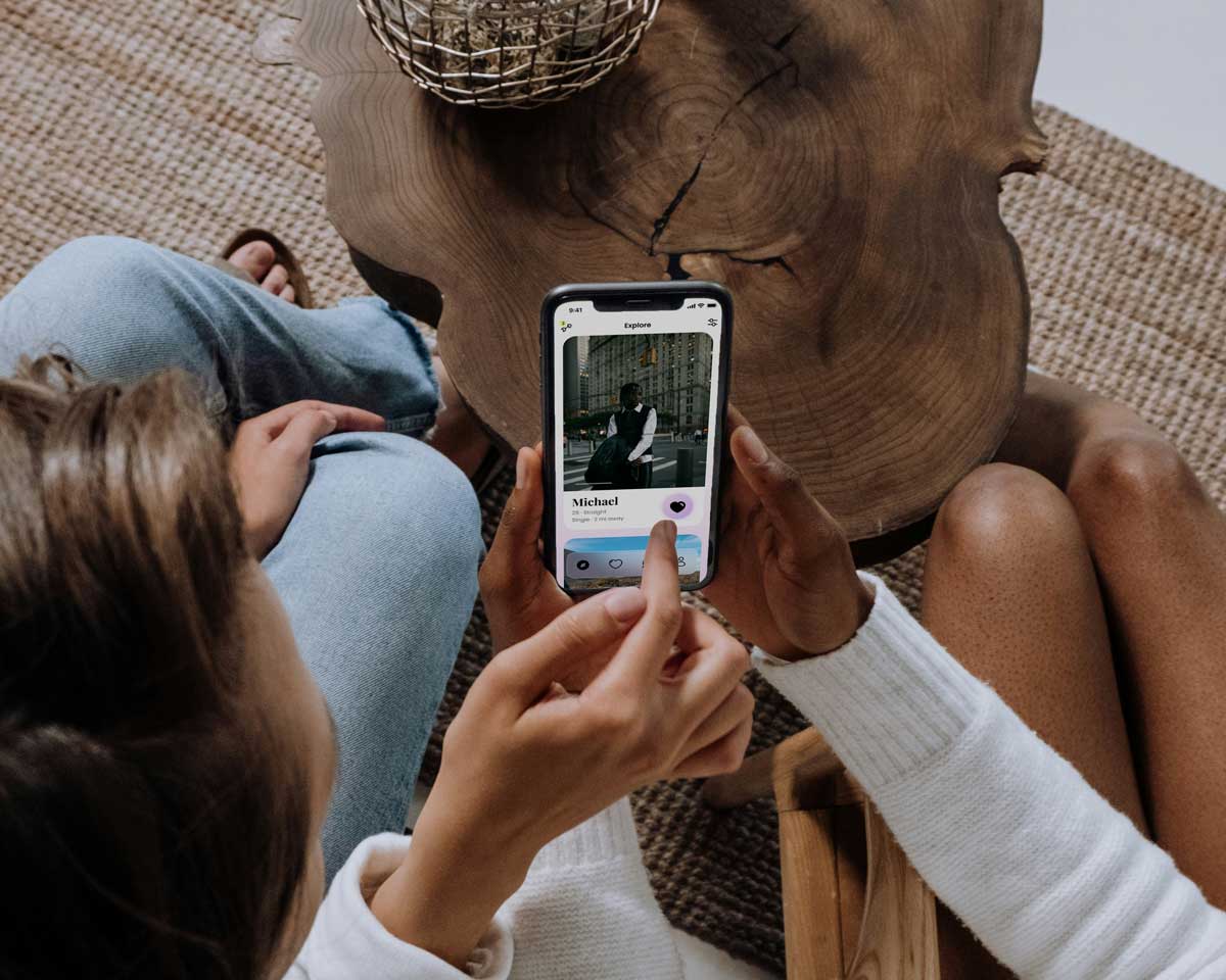 Two Canadians swiping on a dating app, discussing if they would get the best results by paying for the premium plan.