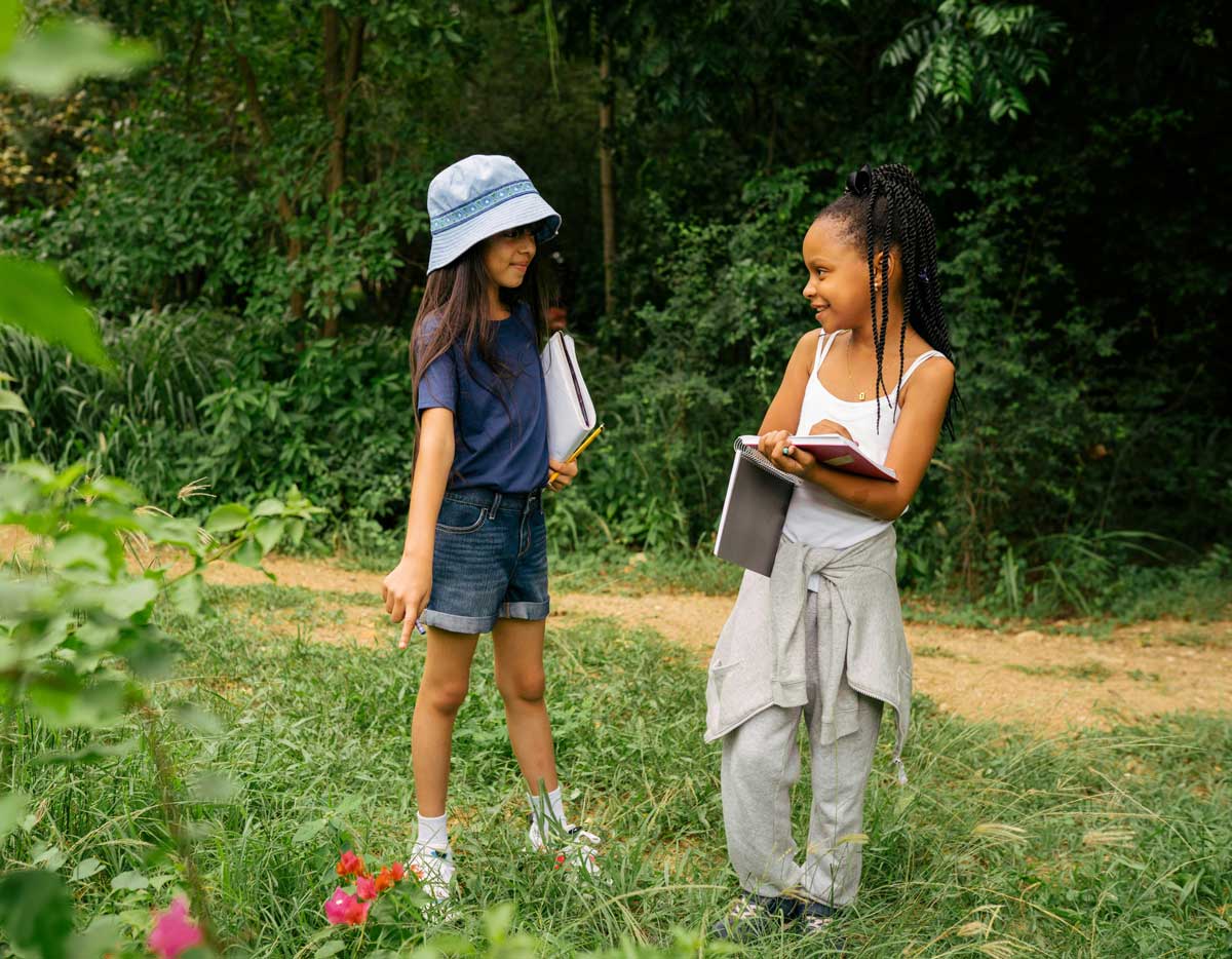 Two Canadian girls at a summer camp participating in a flower scavenger hunt. Their parents were able to save on booking their spots and save.