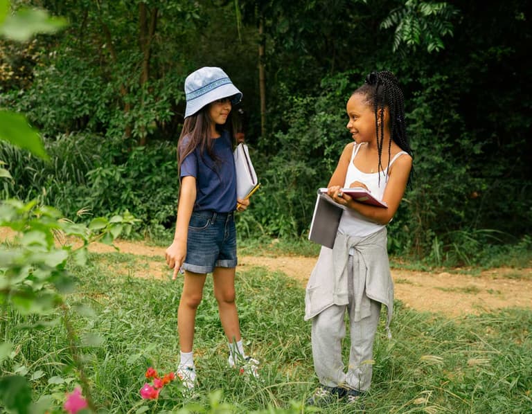 Two Canadian girls at a summer camp participating in a flower scavenger hunt. Their parents were able to save on booking their spots and save.