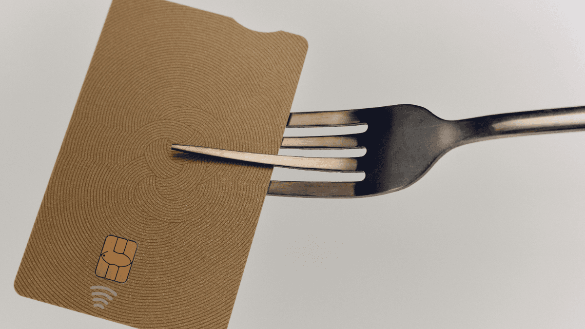 A credit card held by a fork, symbolizing the truth about carrying a balance on your credit card.