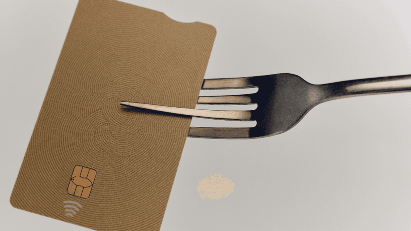 A credit card held by a fork, symbolizing the truth about carrying a balance on your credit card.