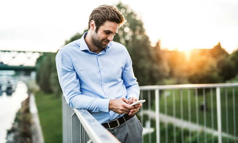 A Canadian man looking at his phone confidently, thinking he's to smart to be scammed.
