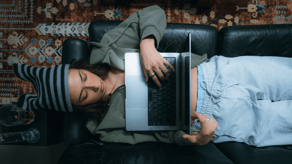 A person laying on a couch while using their laptop, searching up on the unexpected effects of doing a consumer proposal in Canada