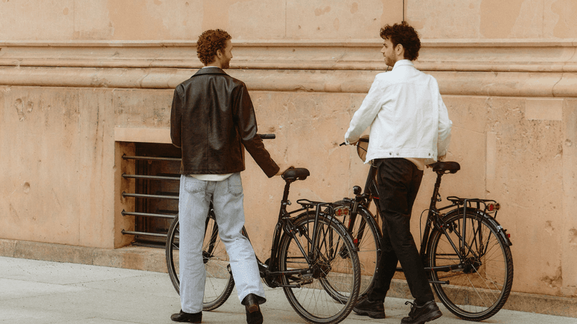 Two friends walking alongside their bicycles, discussing the pros and cons of the Wealthsimple credit card vs. Neo Everywhere card