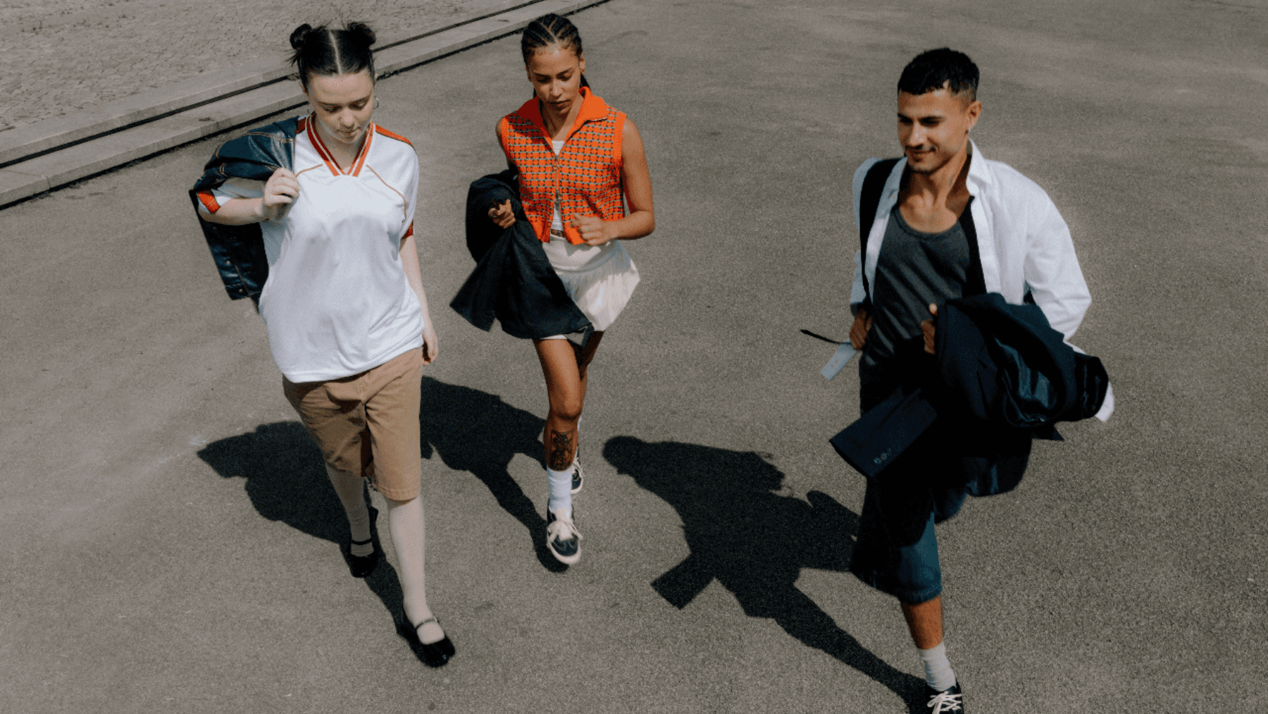Three teens walking side-by-side on a sunny day, trying to find out what age they can get a credit card in Canada