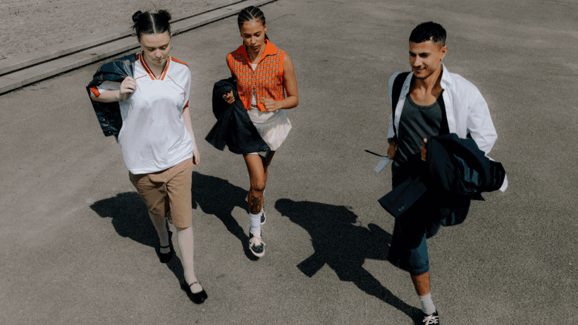 Three teens walking side-by-side on a sunny day, trying to find out what age they can get a credit card in Canada