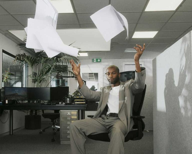 A Canadian man at his job, throwing paper up in the air, because he hasn’t been able to see his raise reflected in his paycheque.
