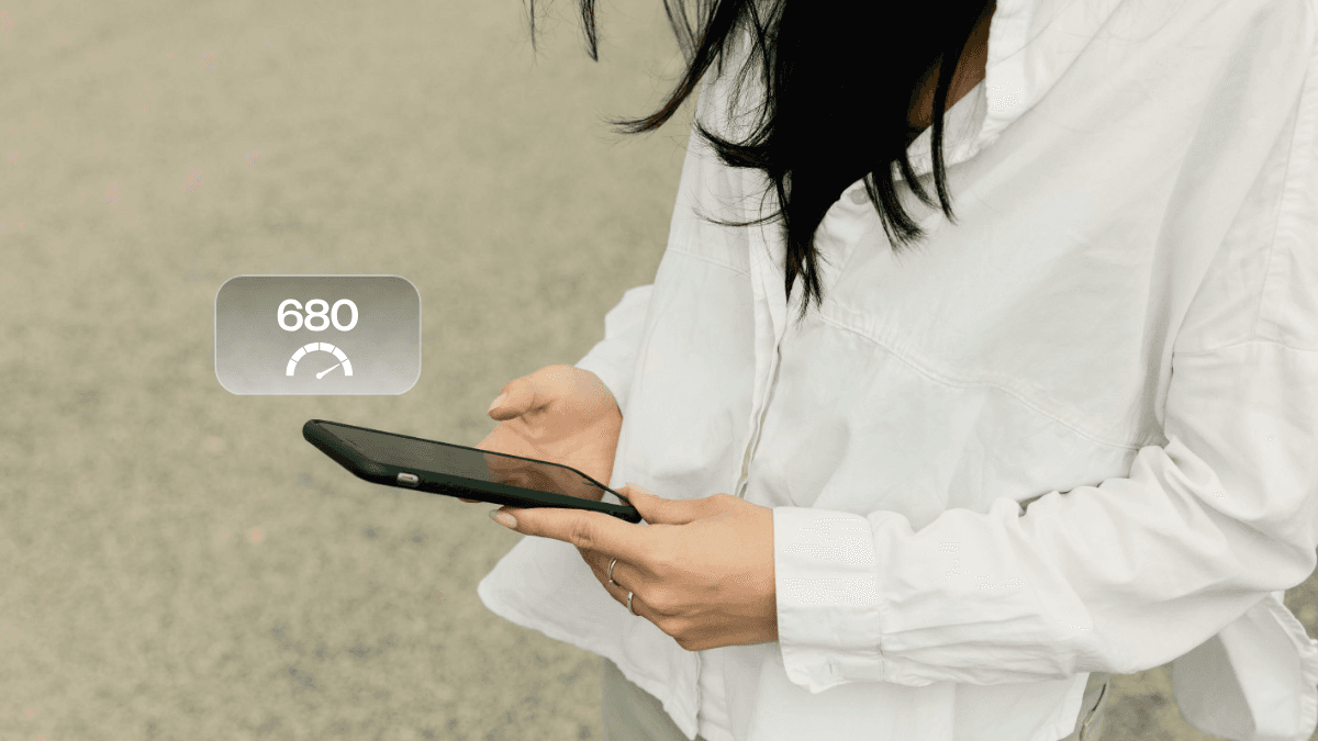 A person in a white button-down shirt and using a smartphone, checking what they can and can't do with a 680 credit score in Canada