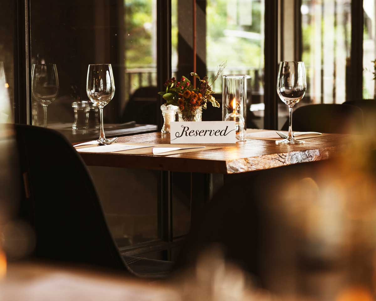 A table for two at a Canadian restaurant with a reserved tent sign on the table, showing that there could be a conversation, or even expectations, around who is to pay for a date.